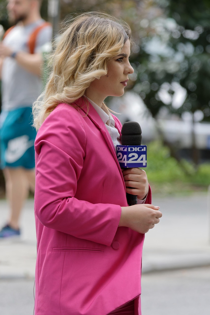 woman, news anchor, reporter, pink suit, standing, speaking, reportage, interview, street, urban, city